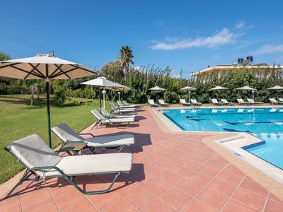 Espace piscine ensoleillé avec transats et parasols dans un jardin d'hôtel.