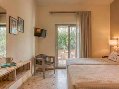 Chambre d'hôtel confortable avec lit double, chaise, TV et accès au balcon.