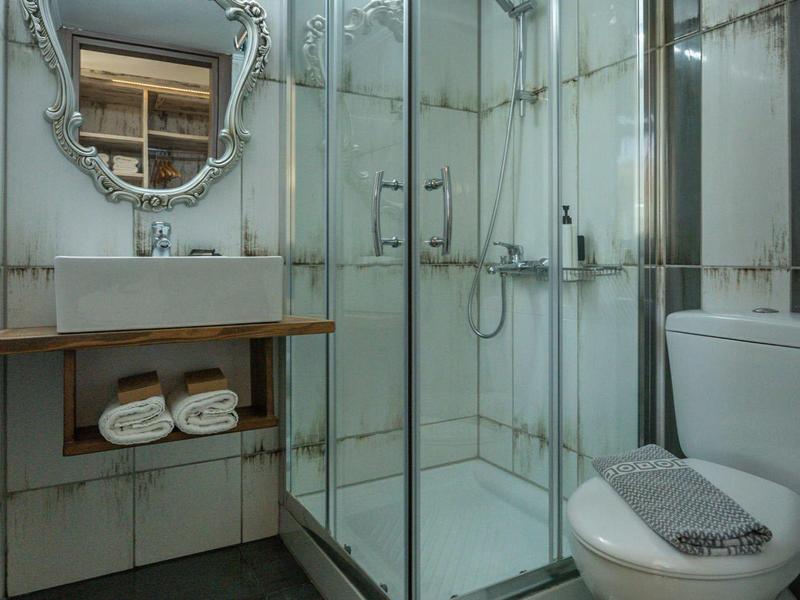 Salle de bain moderne avec douche en verre, toilettes et miroir décoratif dans une chambre d'hôtel.