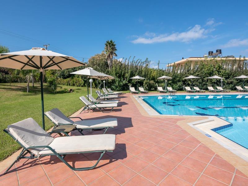 Espace piscine ensoleillé avec transats et parasols dans un jardin d'hôtel.
