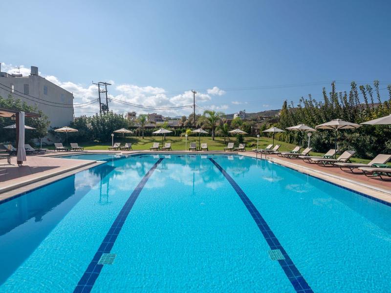 Piscine extérieure avec chaises longues et environnement verdoyant par une journée ensoleillée.