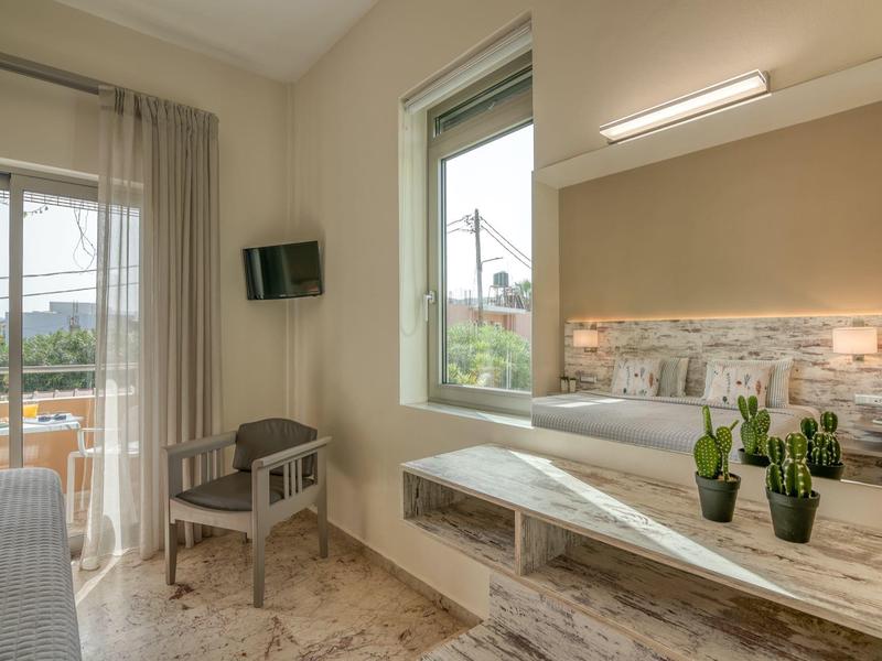 Chambre d'hôtel moderne avec lits jumeaux, bureau, chaise, fenêtre et balcon avec vue extérieure.