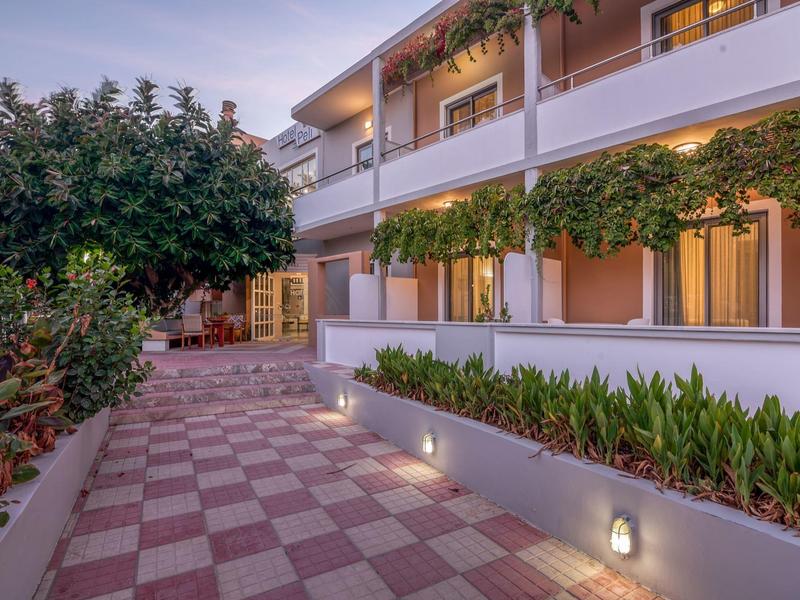 Allée éclairée avec plantes et balcons dans un hôtel moderne au crépuscule.