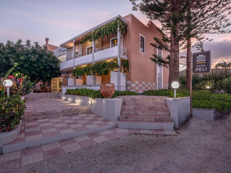 Immeuble d'hôtel à deux étages avec balcons et éclairage extérieur au coucher du soleil.