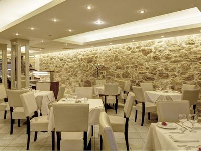 Sala de comedor de hotel con sillas beige y paredes de piedra iluminadas elegantemente.