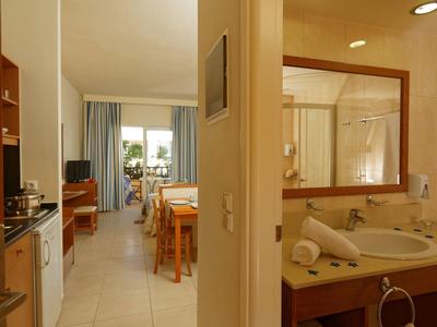 Vista de una habitación de hotel con cocina, mesa de comedor y área de dormir con ventana.