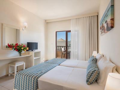 Habitación de hotel luminosa con cama doble, balcón y decoración moderna.