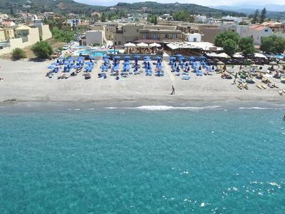 Blick auf einen belebten Strand mit Sonnenschirmen und Gebäuden im Hintergrund.