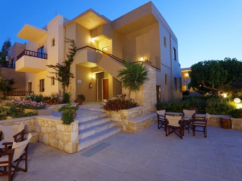 Hotel iluminado con terraza, zonas de asiento y plantas en tranquila atmósfera vespertina.