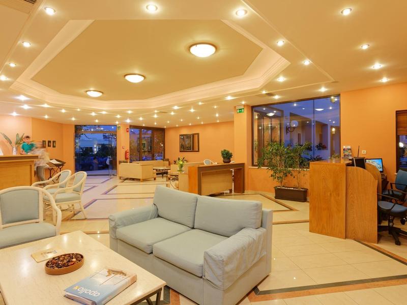 Lobby de hotel iluminada con sofás, recepción y área de trabajo con luz cálida.