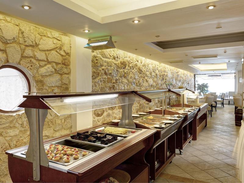 Línea de buffet con diversas comidas en un restaurante bien iluminado con paredes de piedra.