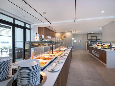 Modern buffet with warm lighting and large windows in a hotel restaurant.