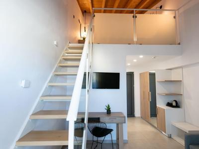 Modern room with open staircase, workspace, and TV in bright design.