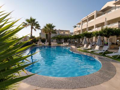 Runder Hotelpool mit Liegestühlen und Sonnenschirmen unter blauem Himmel.