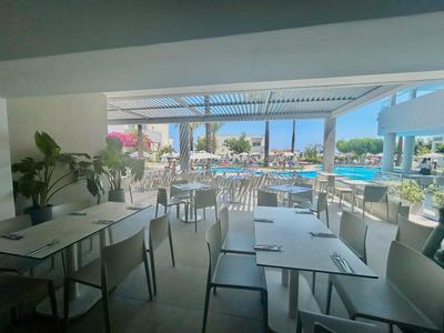 Moderner Außenbereich eines Restaurants mit Blick auf einen Pool und Sitzgelegenheiten unter einem Sonnendach.