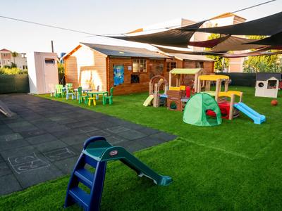 Kinderspielplatz mit Rutschen und Klettergeräten im Hotelaußenbereich bei Sonnenschein.