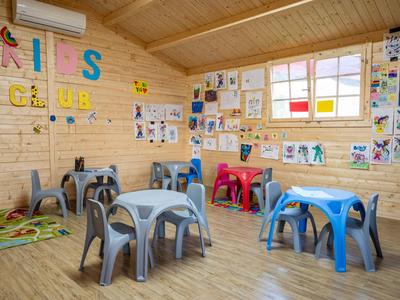 Innenraum eines Kinderclubs mit bunten Tischen, Stühlen und Wanddekoration aus Holz gebaut.