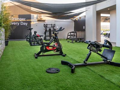 Gym mit modernen Geräten auf grünem Kunstrasen, hell beleuchtet und überdacht.