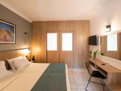 Modern hotel room with double bed, desk, and wood paneling on the wall.