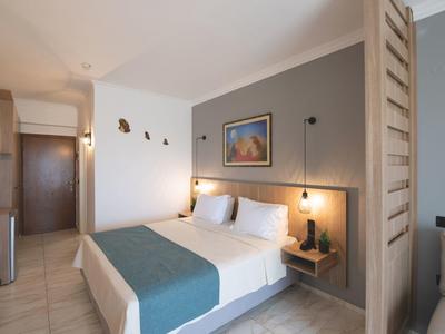 Modern hotel room with double bed, nightstands, and a separate seating area.