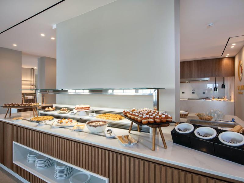 Buffet area with cakes, pastries, and dishes in a modern hotel restaurant.