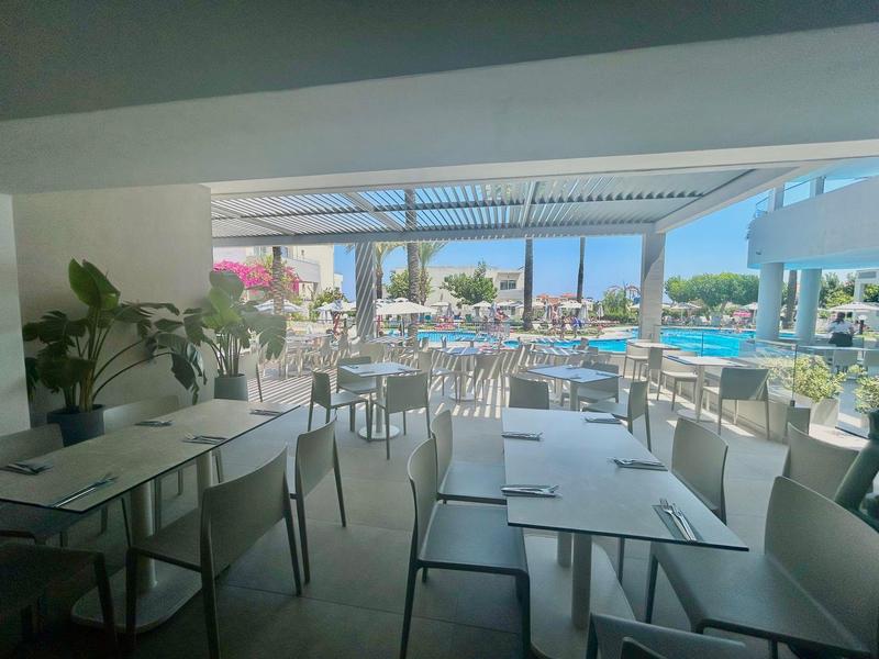Outdoor restaurant with white tables and chairs near hotel pool