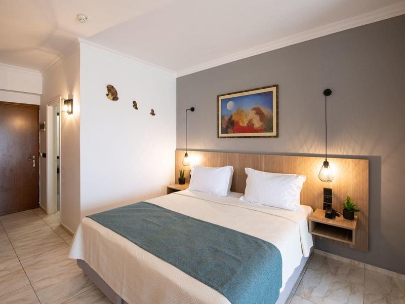 Modern hotel room with double bed, wall lighting, and decorative painting above the bed.