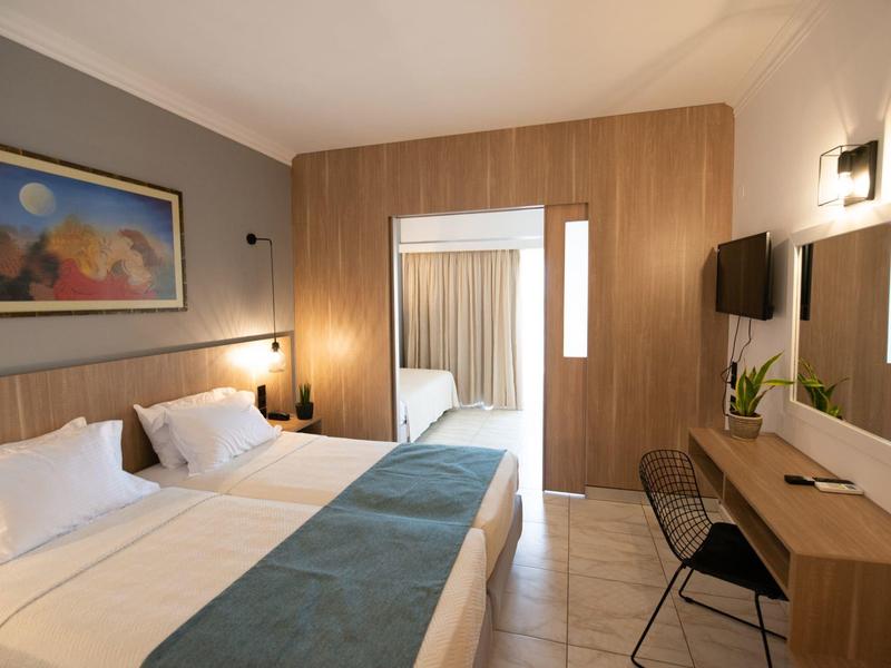 Modern hotel room with double bed, desk, and flat-screen TV.