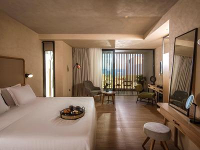 Modern hotel room with double bed, terrace, and green view.