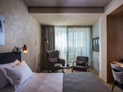 Cozy hotel room with double bed, armchairs, and large window with curtains.