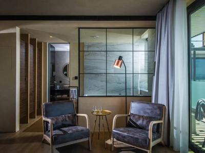 Coin salon moderne de chambre d'hôtel avec deux fauteuils en cuir, petite table d'appoint et vue sur le balcon.
