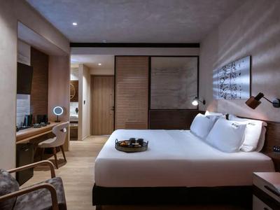 Chambre d'hôtel moderne avec lit double, boiseries et bureau sous un éclairage chaud.