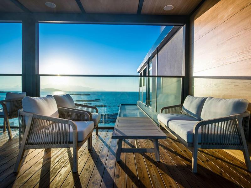 Balcony with chairs and sofa overlooking the sea at sunset.