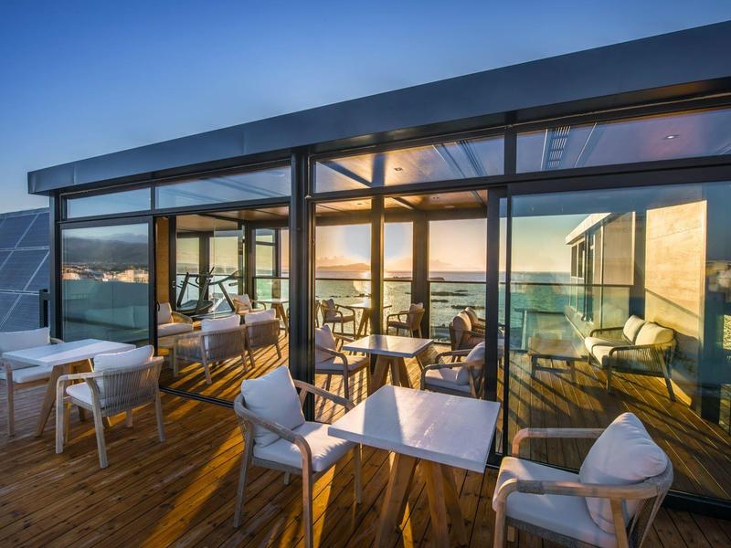 Rooftop terrace with seating area and panoramic sea view at sunset.