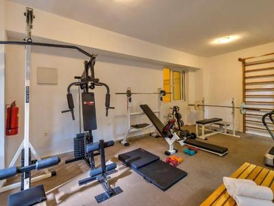 Kleines Fitnessstudio mit verschiedenen Trainingsgeräten und Hanteln in einem Hotelraum.