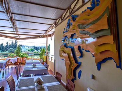 Überdachte Terrasse mit weißen Tischen und Stühlen, Wanddekoration mit Meeresthema, Blick auf Garten