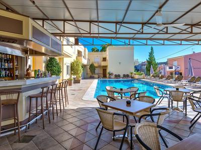 Freie Terrasse mit Stühlen, Bar und einem klaren blauen Pool unter einem transparenten Dach.