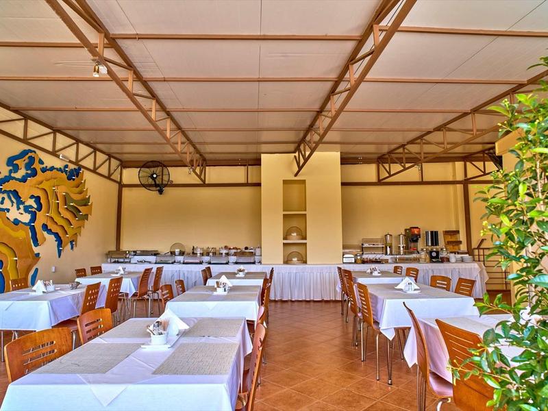 Zastřešená venkovní jídelní část s bílými ubrusy a dřevěnými židlemi.