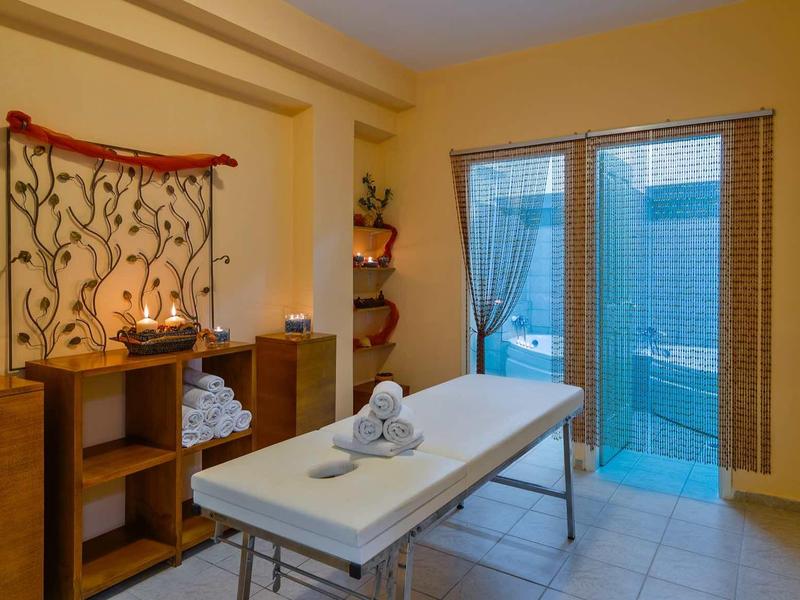 Pohodlná spa místnost s masážním stolem, svíčkami a relaxační výzdobou u skleněných oken.