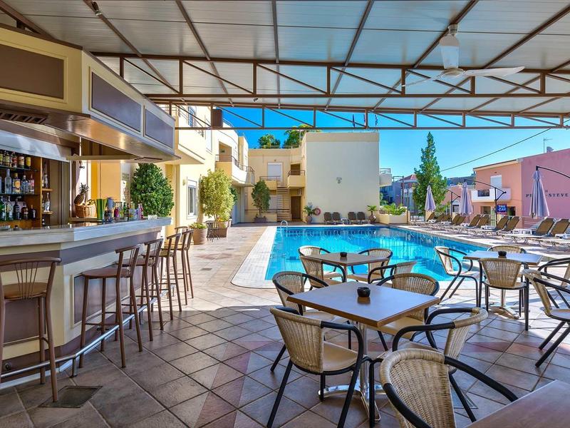 Moderní venkovní prostor s barem, stoly a bazénem v hotelu.