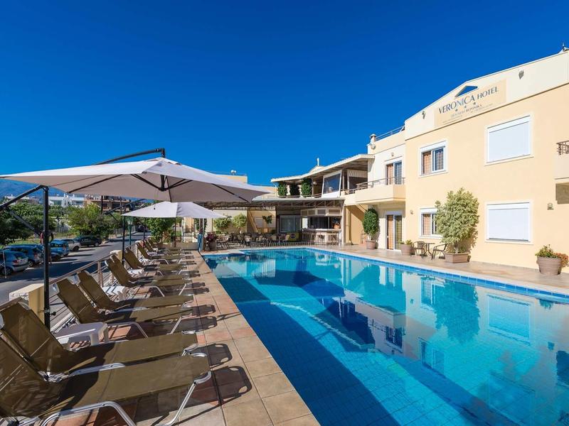 Hotel s velkým venkovním bazénem a lehátky pod slunečníky za jasného dne