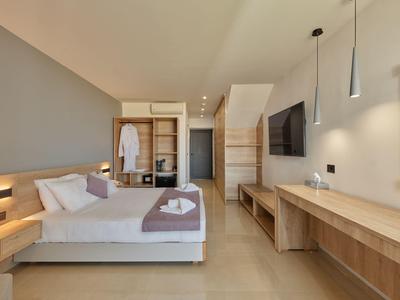 Modern eingerichtetes Hotelzimmer mit großem Bett, Holzmöbeln und integriertem Schreibtisch.