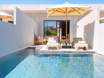Moderner Hotelpool mit weißen Liegestühlen und gelbem Sonnenschirm bei klarem Himmel.