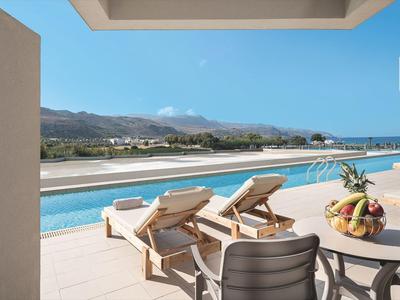 Terras met zwembad, ligstoelen en fruitmand met uitzicht op bergen en zee.