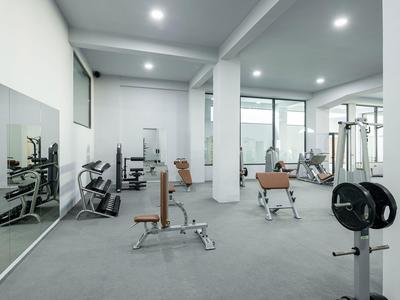 Moderner Fitnessraum mit Geräten und großen Fenstern in einem Hotel.