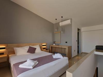Modern hotelkamer met groot bed, grijze muur en minimalistische inrichting.