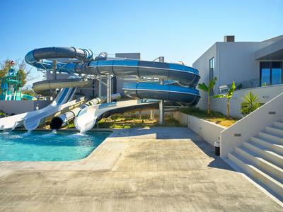 Wasserpark mit großen Wasserrutschen und Pool neben modernem Hotelgebäude bei klarem Himmel.