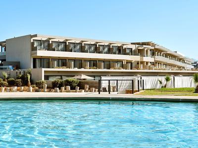 Modernes Hotelgebäude mit Flachdach und Pool in klarem blauen Wasser.