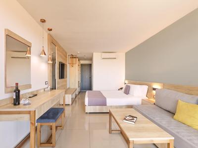 Modern eingerichtetes Hotelzimmer mit Sofa, Bett, Schreibtisch und hellen Wänden.