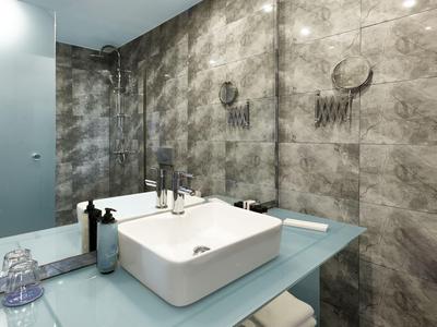 Modernes Badezimmer mit eckigem Waschbecken und spiegelnder grauer Wandgestaltung.
